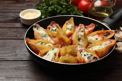 Photo of Delicious shell pasta stuffed with ricotta and spinach served on wooden table, closeup