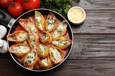 Photo of Delicious shell pasta stuffed with ricotta and spinach served on wooden table, flat lay. Space for text