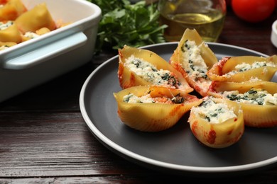 Photo of Delicious shell pasta stuffed with ricotta and spinach served on wooden table, closeup