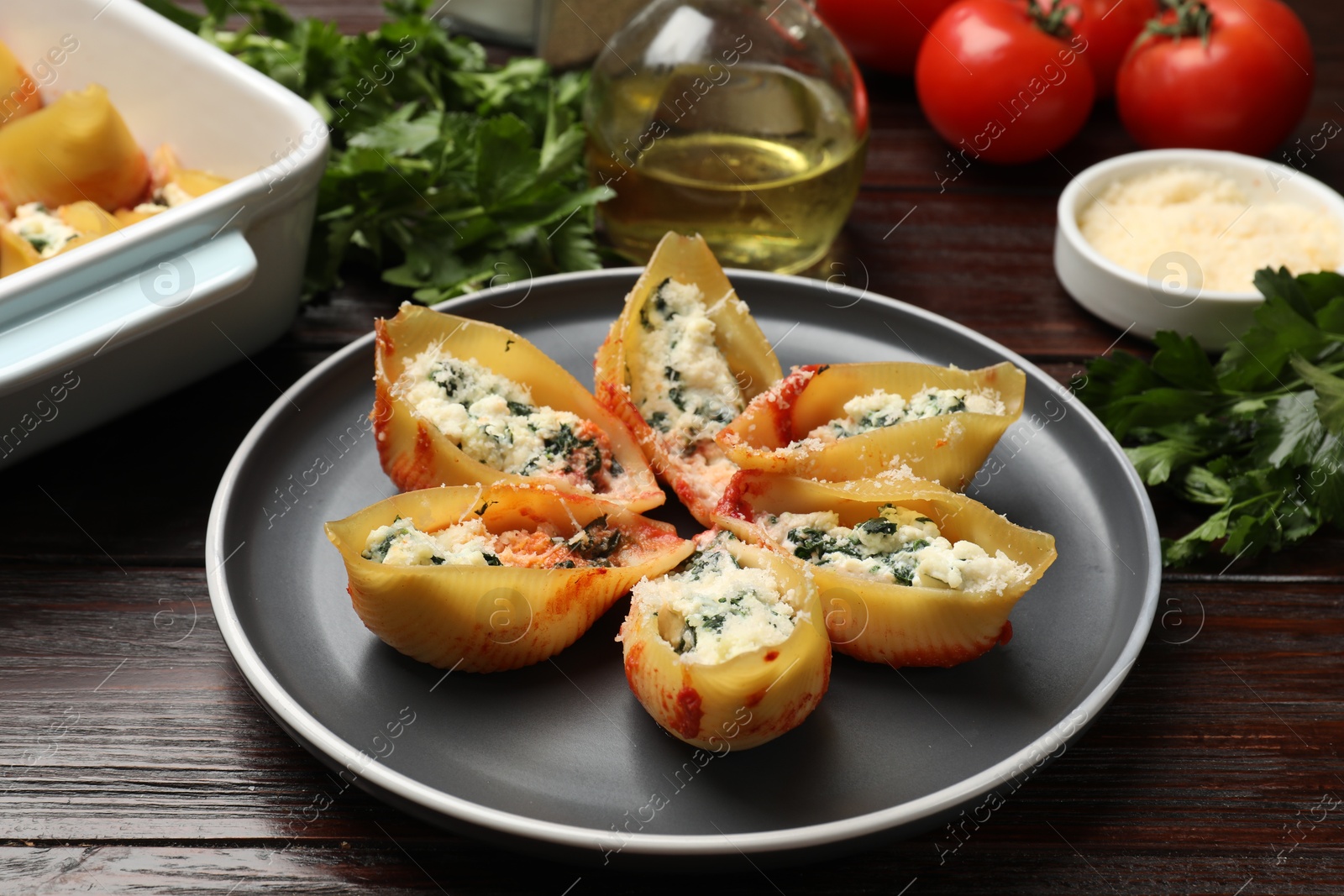 Photo of Delicious shell pasta stuffed with ricotta and spinach served on wooden table, closeup