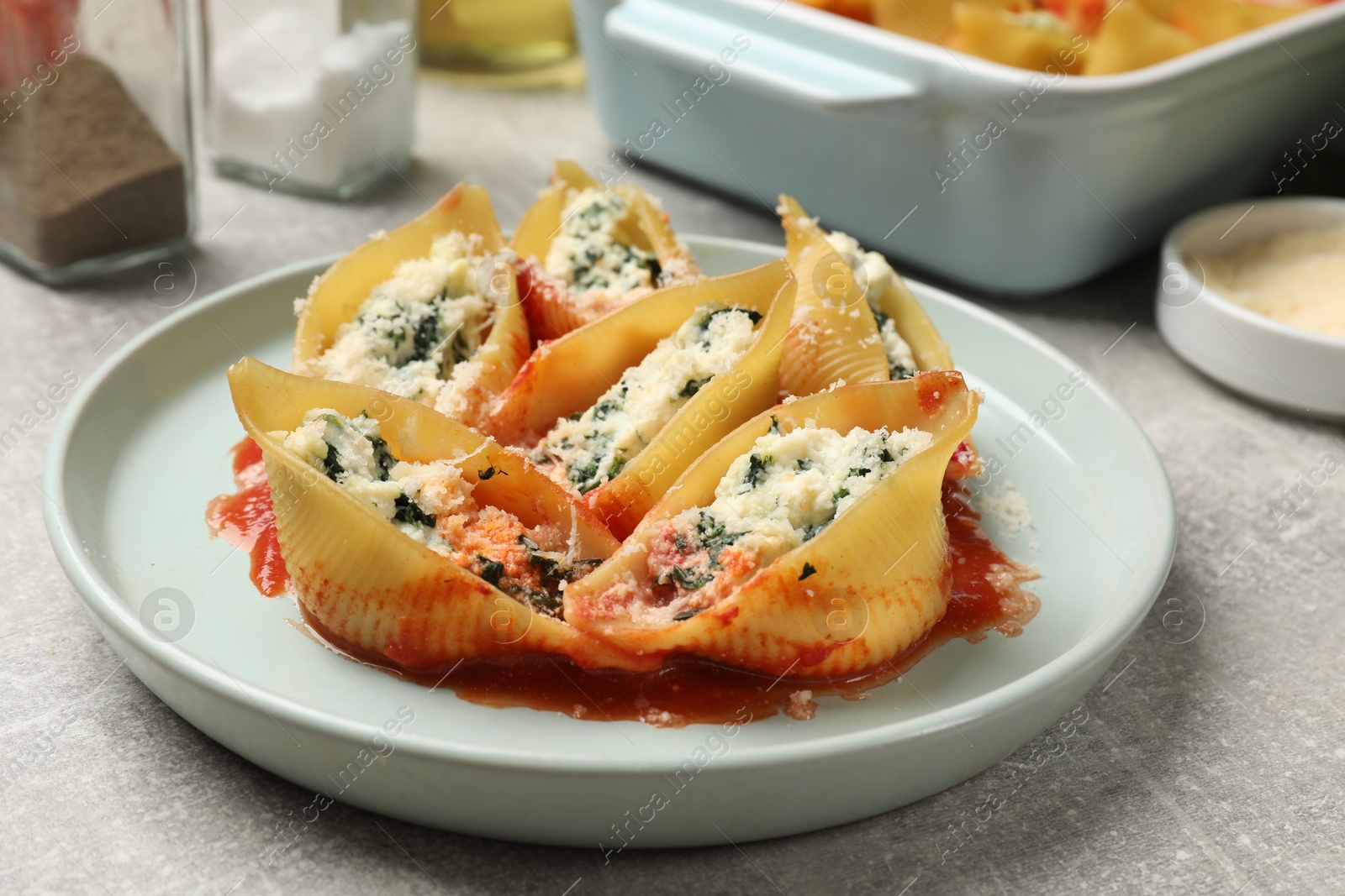 Photo of Delicious shell pasta stuffed with ricotta and spinach served on light grey table, closeup