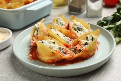 Photo of Delicious shell pasta stuffed with ricotta and spinach served on light grey table, closeup