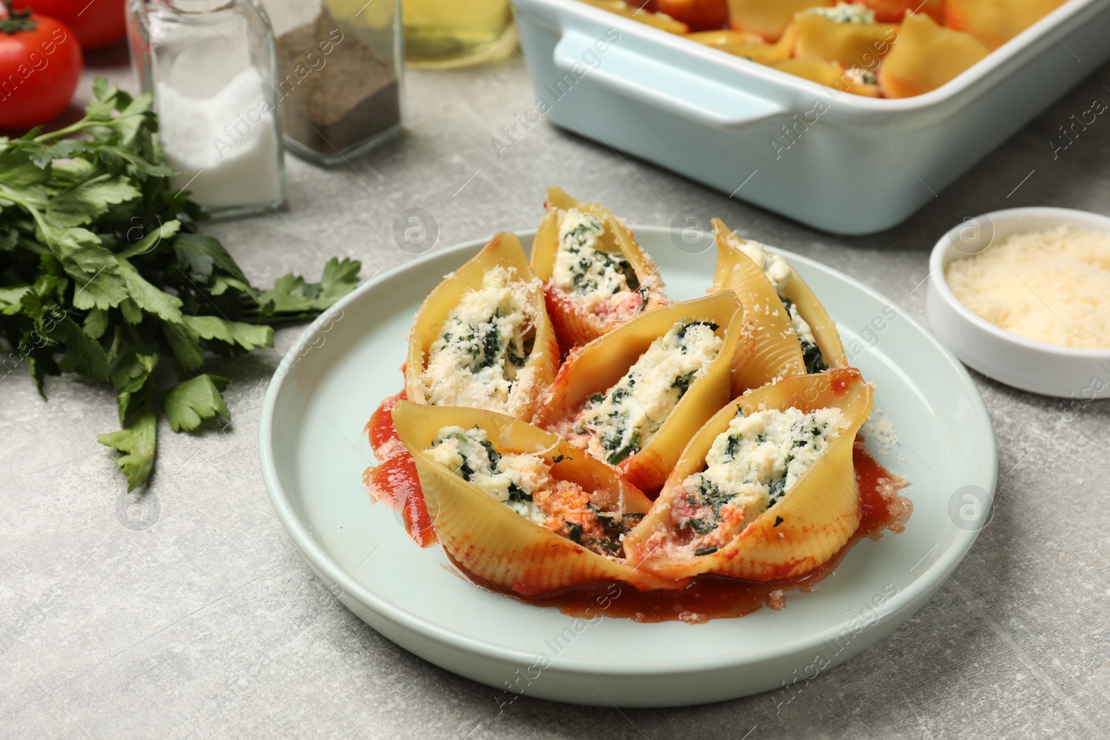 Photo of Delicious shell pasta stuffed with ricotta and spinach served on light grey table, closeup