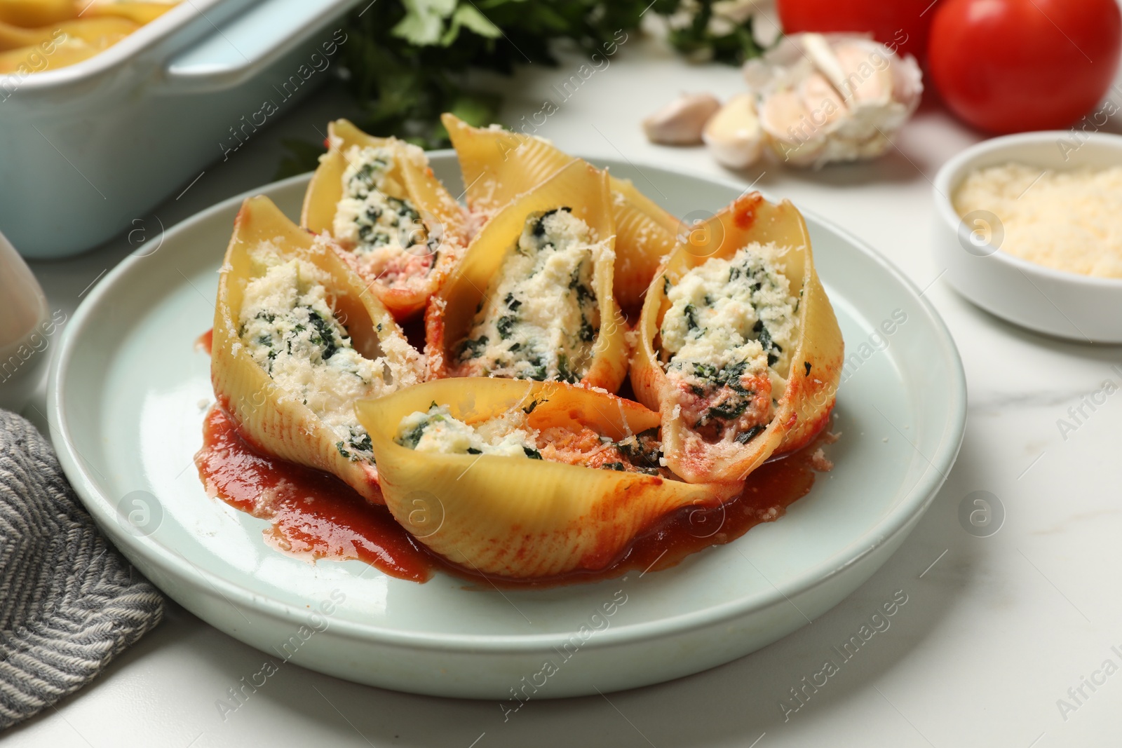 Photo of Delicious shell pasta stuffed with ricotta and spinach served on white table, closeup