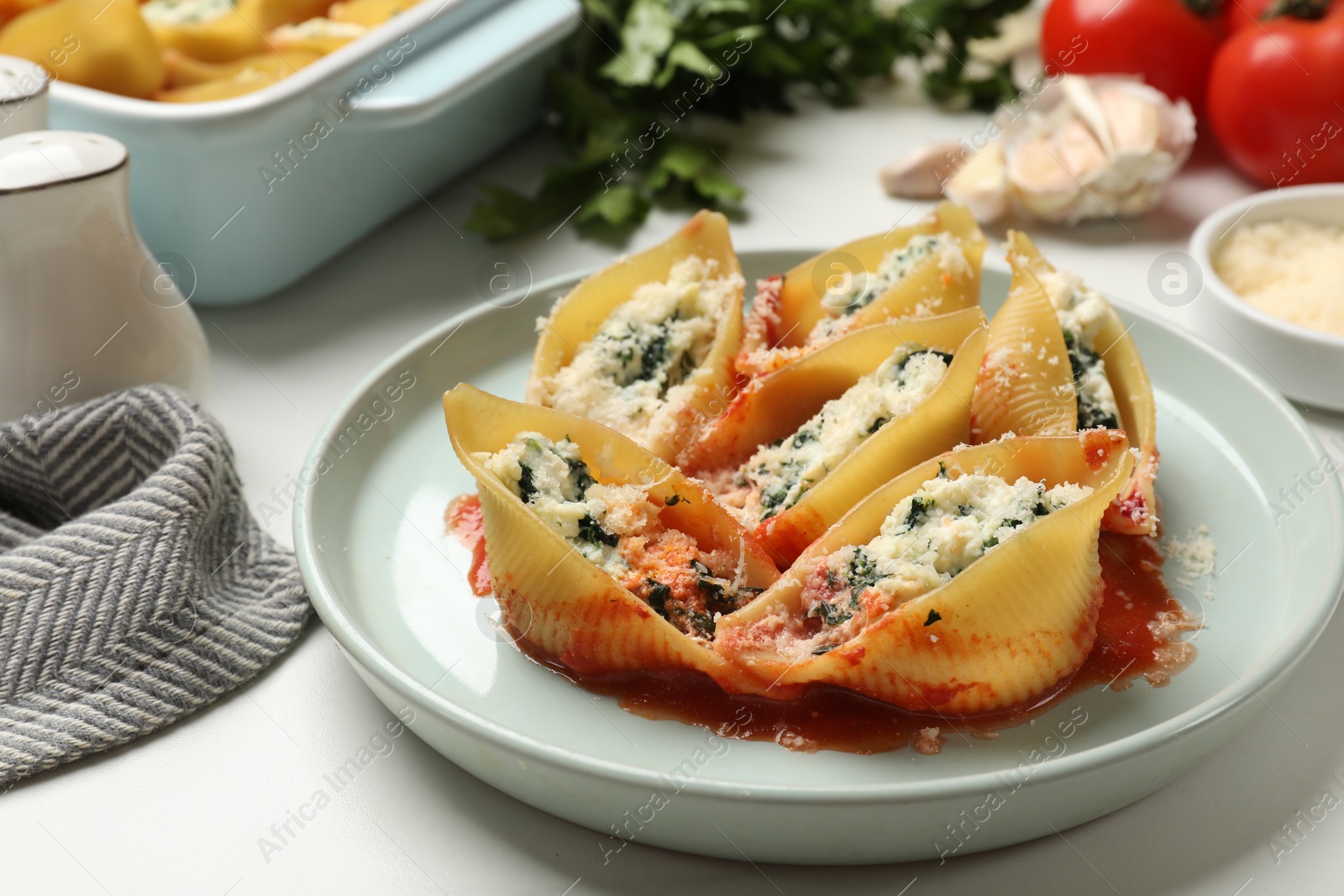 Photo of Delicious shell pasta stuffed with ricotta and spinach served on white table, closeup