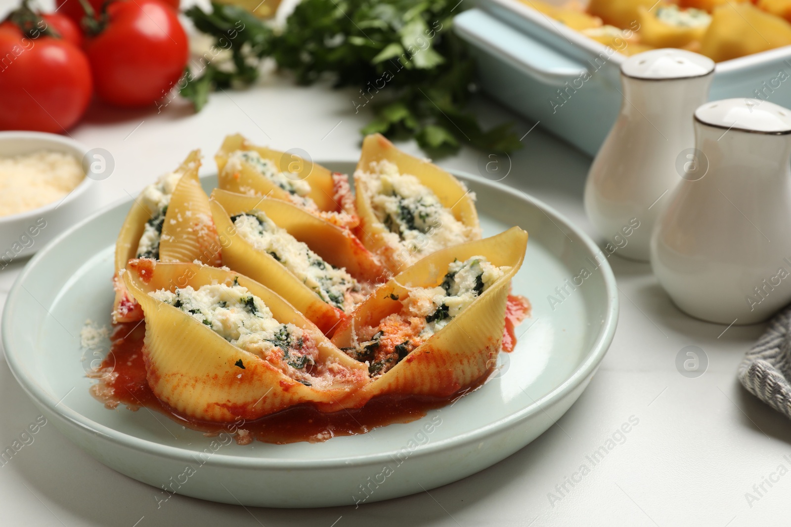 Photo of Delicious shell pasta stuffed with ricotta and spinach served on white table, closeup