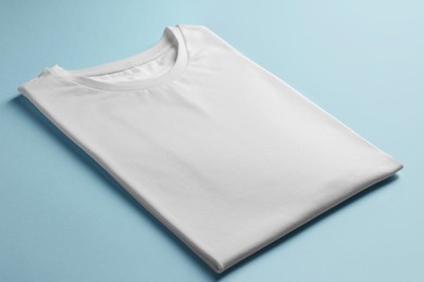 Photo of One blank t-shirt on light blue background, closeup. Mockup for design