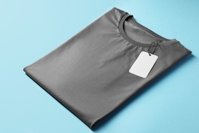 Photo of One blank t-shirt on light blue background, closeup. Mockup for design