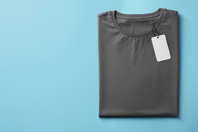 Photo of One blank t-shirt on light blue background, top view. Mockup for design