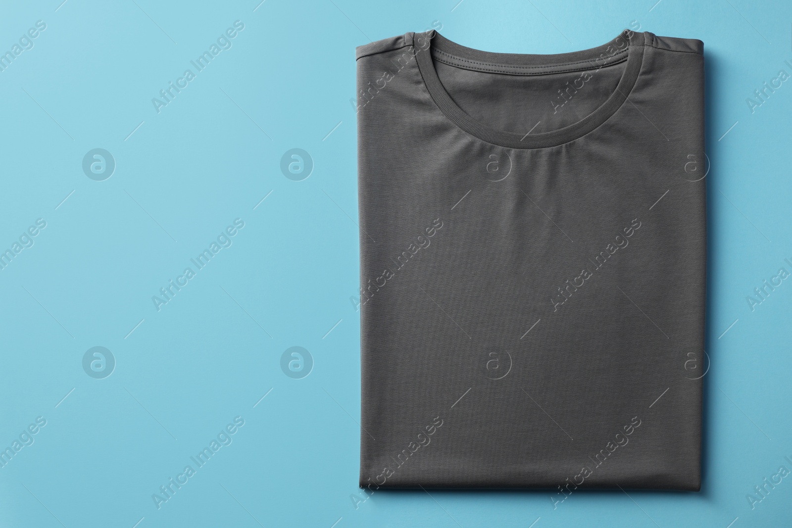 Photo of One blank t-shirt on light blue background, top view. Mockup for design