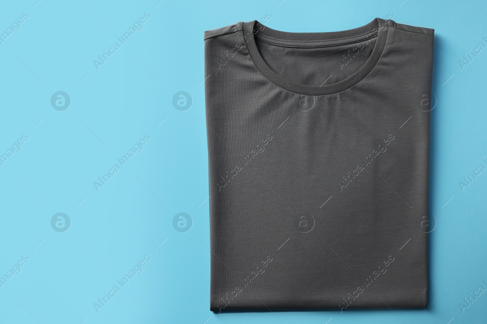 Photo of One blank t-shirt on light blue background, top view. Mockup for design