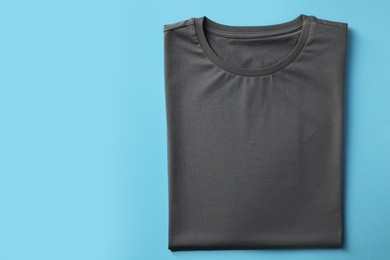 Photo of One blank t-shirt on light blue background, top view. Mockup for design