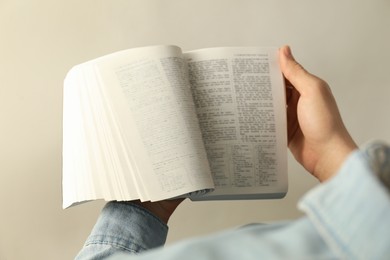 Photo of Man reading Holy Bible in English language on light background, closeup