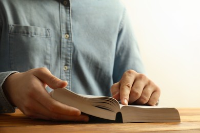 Photo of Man reading Holy Bible at wooden table, closeup