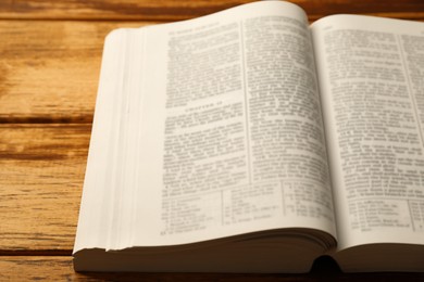 Photo of Open Holy Bible in English language on wooden table, closeup