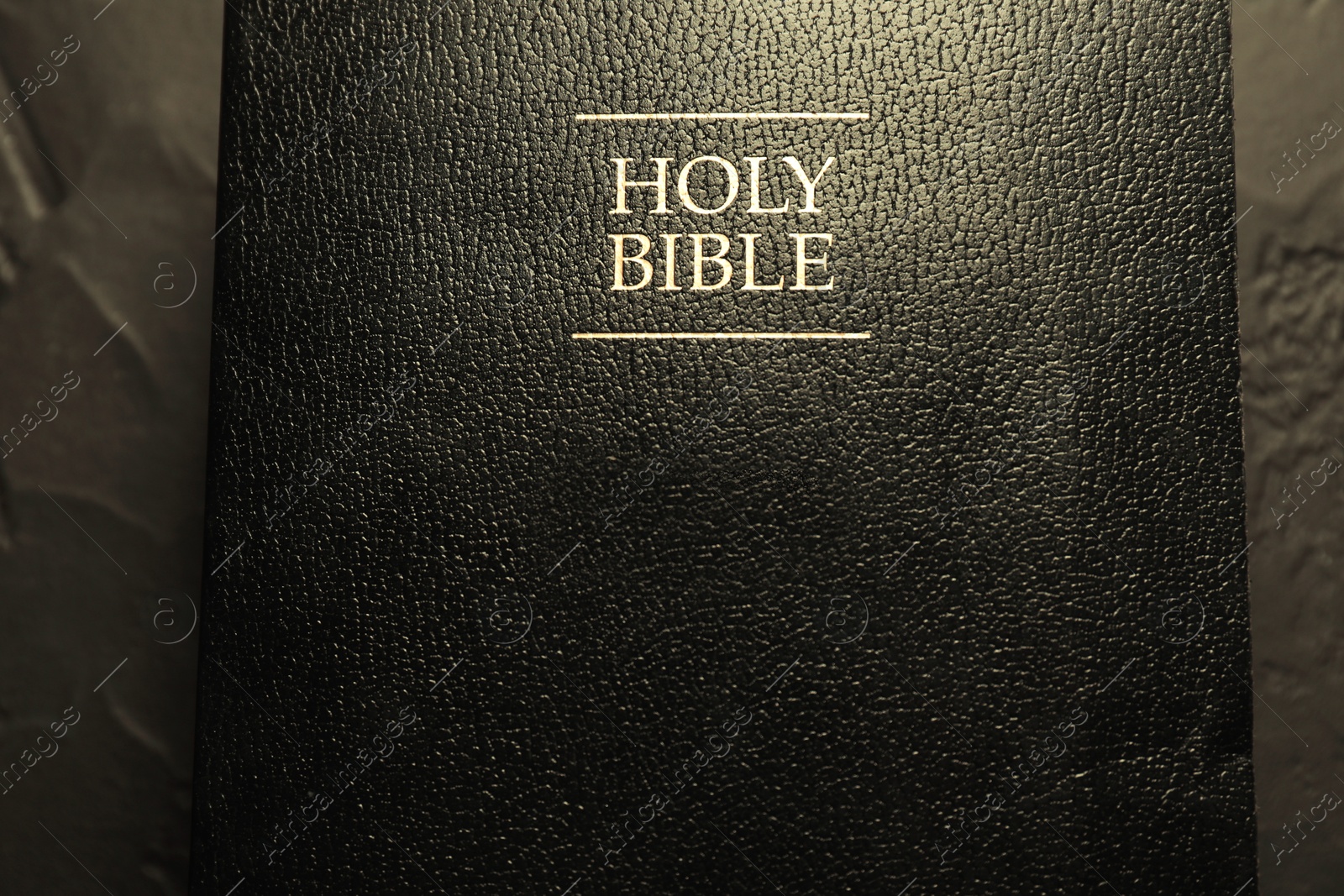 Photo of Hardcover Holy Bible in English language on black table, top view