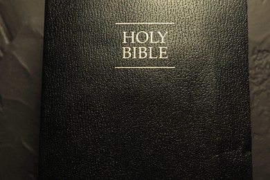 Photo of Hardcover Holy Bible in English language on black table, top view