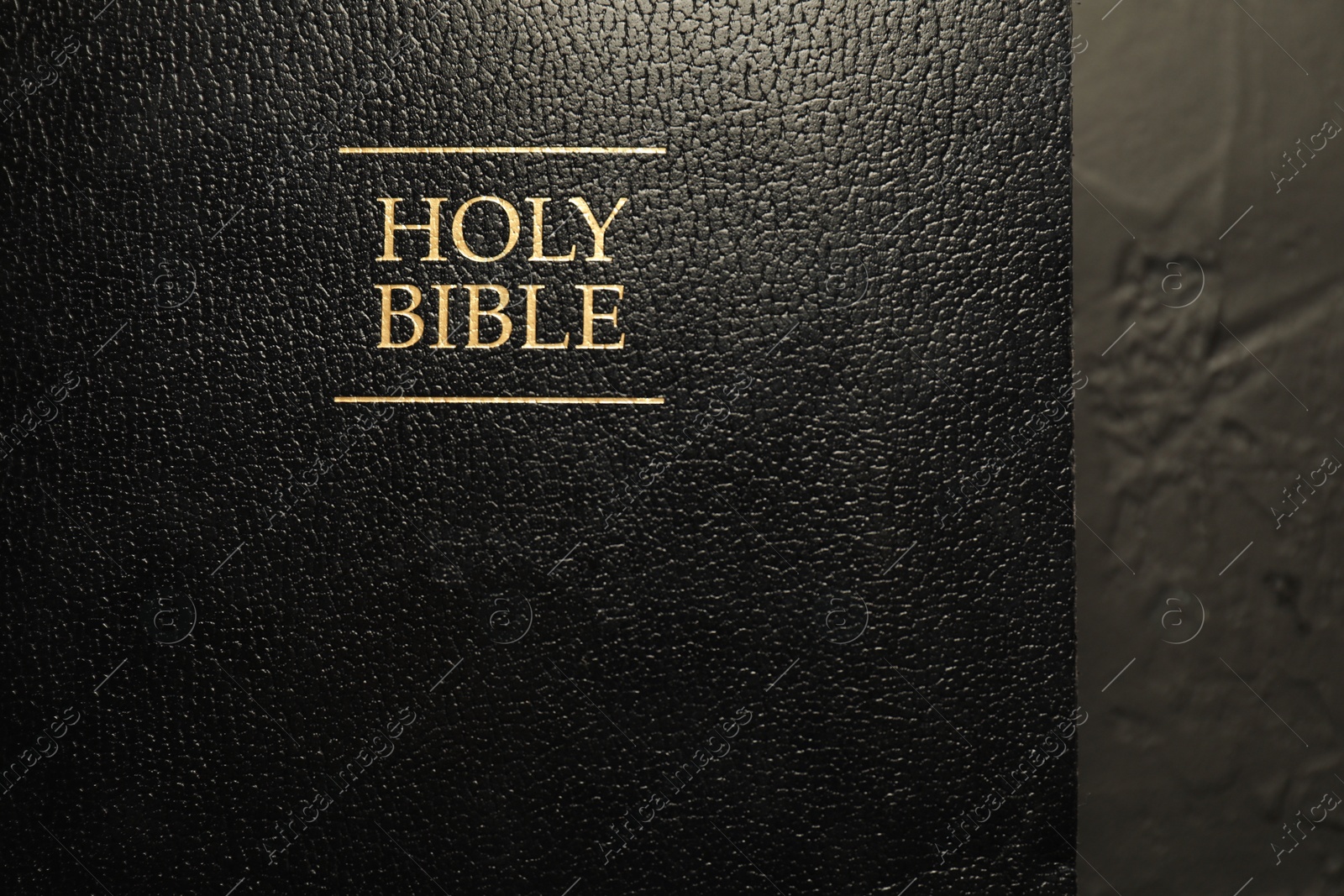 Photo of Hardcover Holy Bible in English language on black table, top view