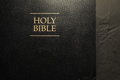 Photo of Hardcover Holy Bible in English language on black table, top view