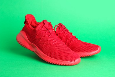 Photo of Pair of stylish red sneakers on green background