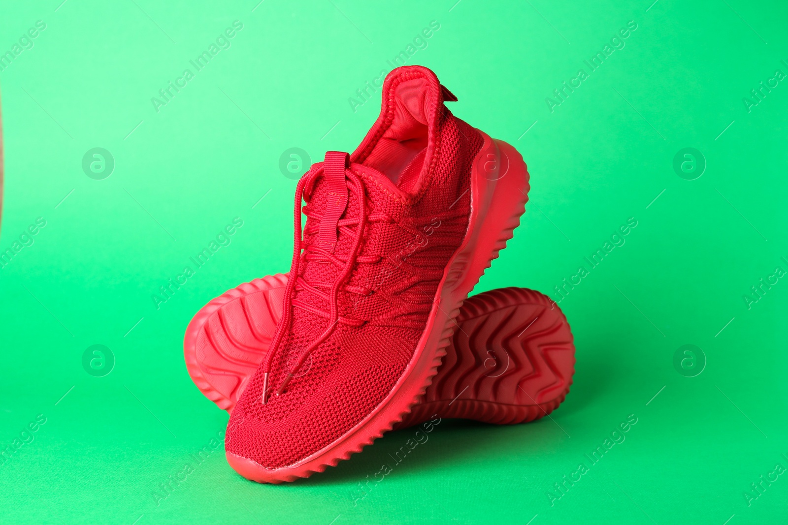 Photo of Pair of stylish red sneakers on green background