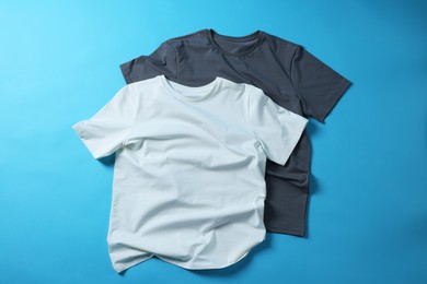 Photo of Blank t-shirts on light blue background, flat lay. Mockup for design