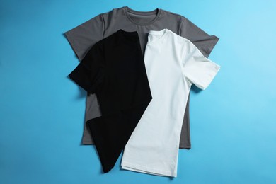 Photo of Blank t-shirts on light blue background, flat lay. Mockup for design