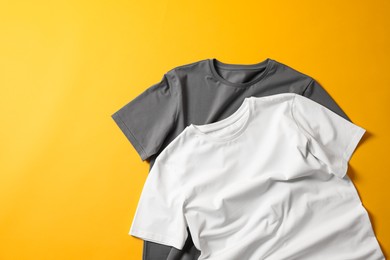 Photo of Blank t-shirts on yellow background, flat lay. Mockup for design