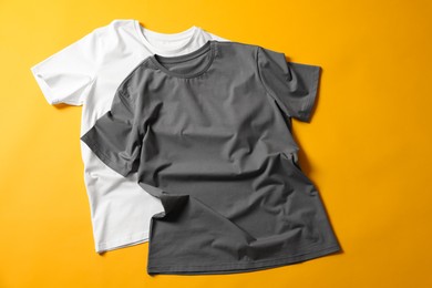 Photo of Blank t-shirts on yellow background, flat lay. Mockup for design