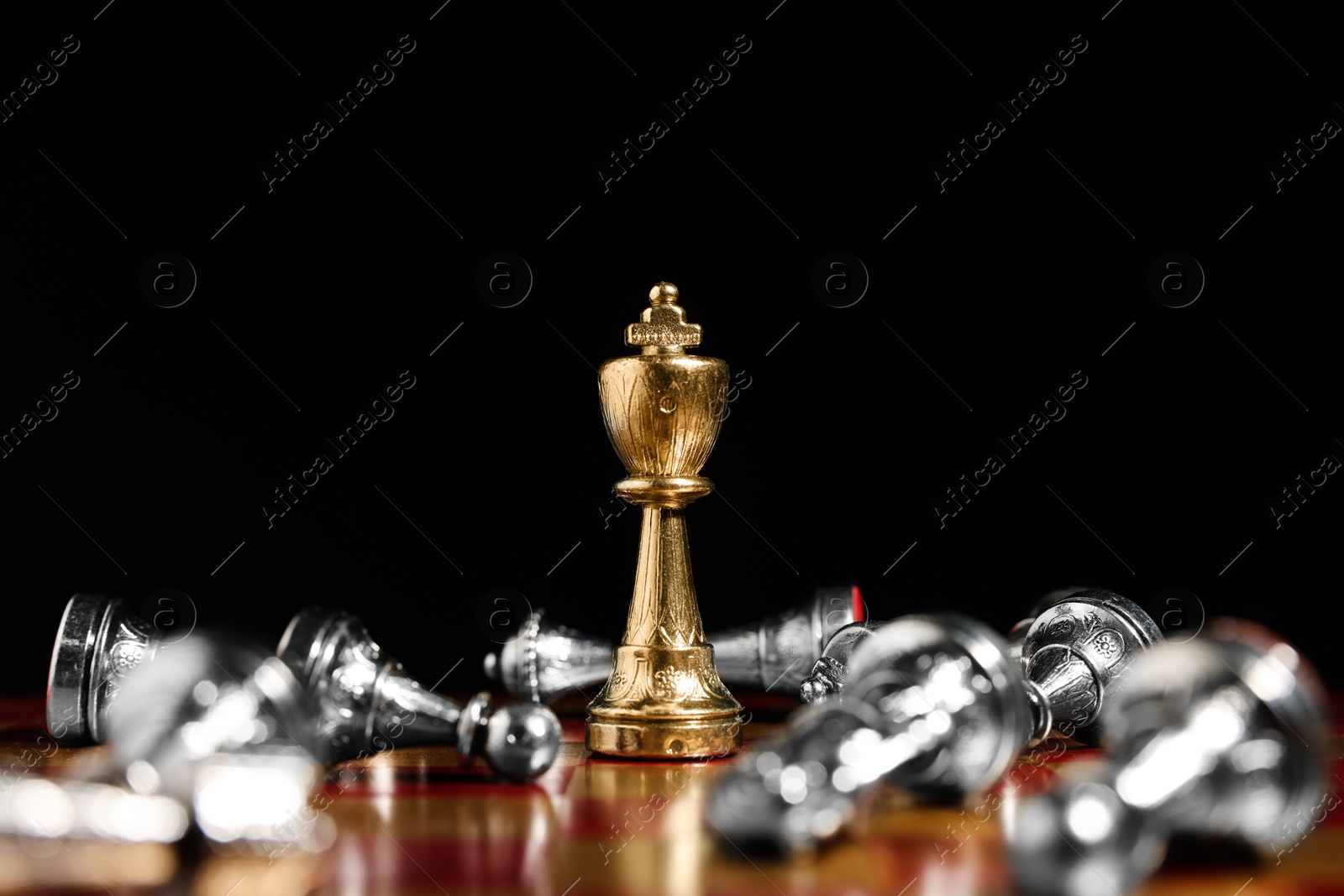 Photo of Golden chess king among fallen silver pieces on chessboard against black background, closeup. Competition concept