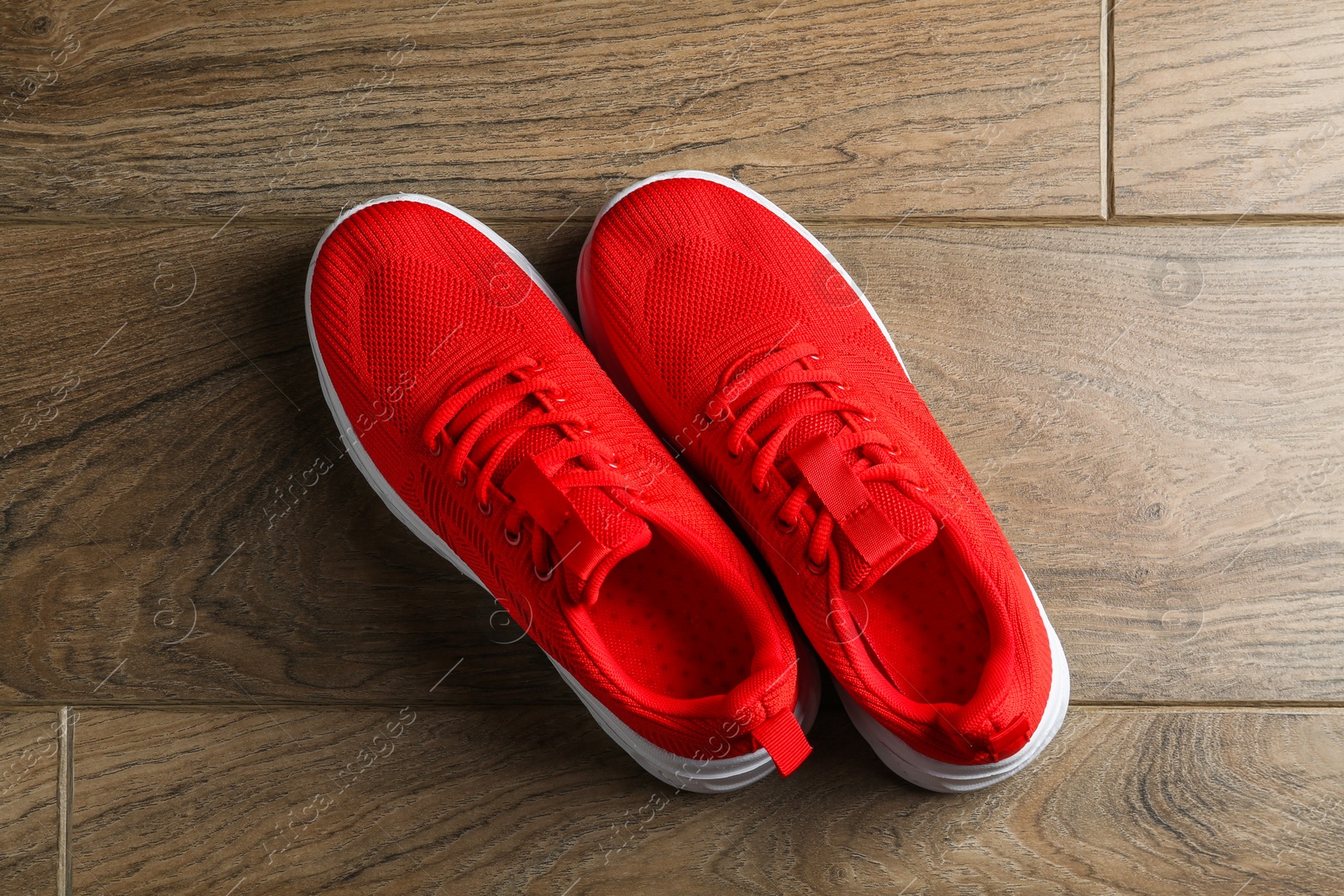 Photo of Pair of stylish red sneakers on wooden background, top view