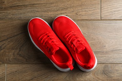 Photo of Pair of stylish red sneakers on wooden background, top view