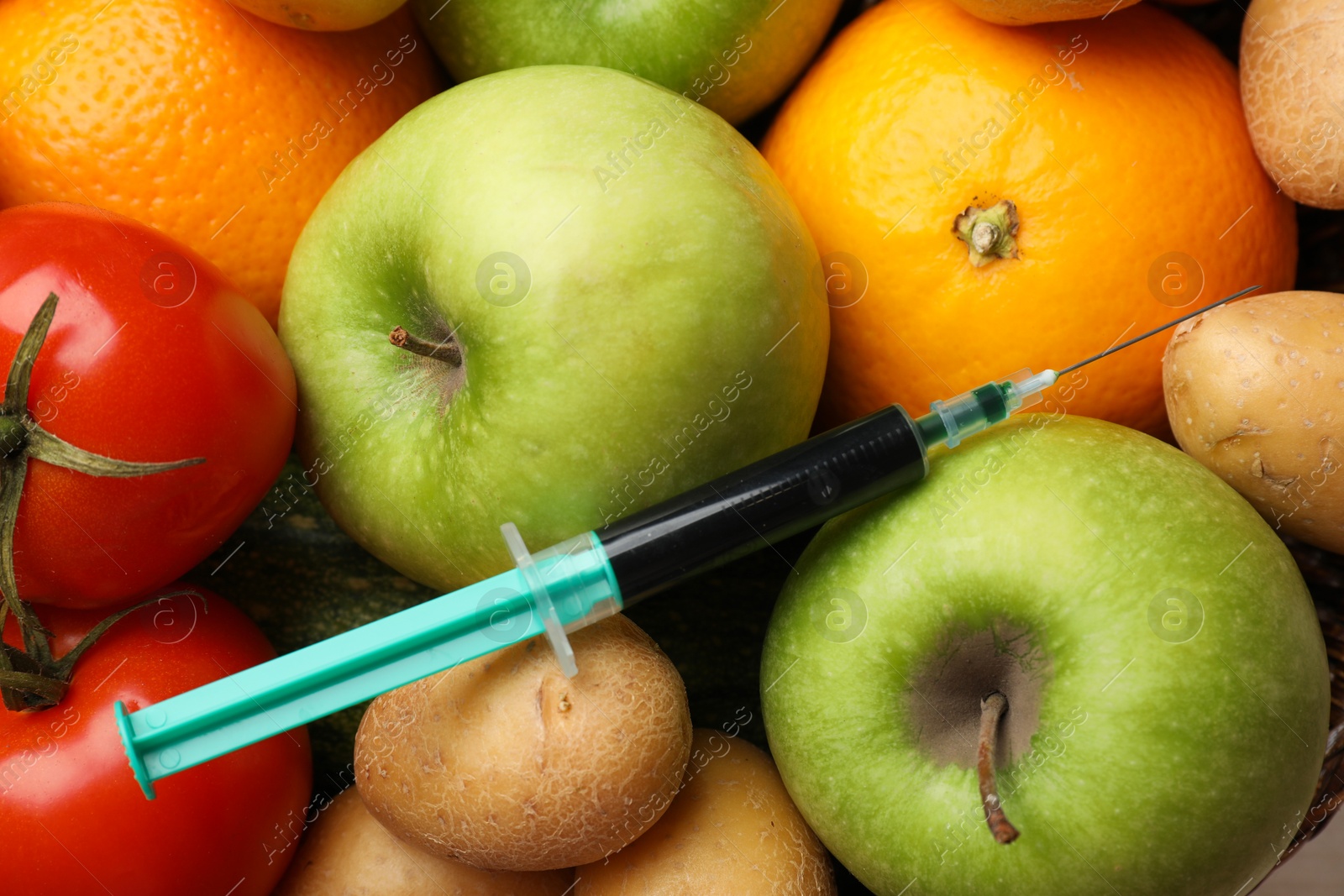 Photo of GMO concept. Different vegetables, fruits and syringe as background, top view