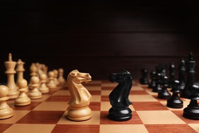 Photo of Black and white chess knights in middle of chessboard. Competition concept