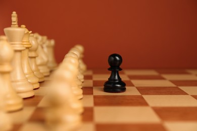 Photo of Black pawn in front of other white chess pieces on chessboard. Competition concept