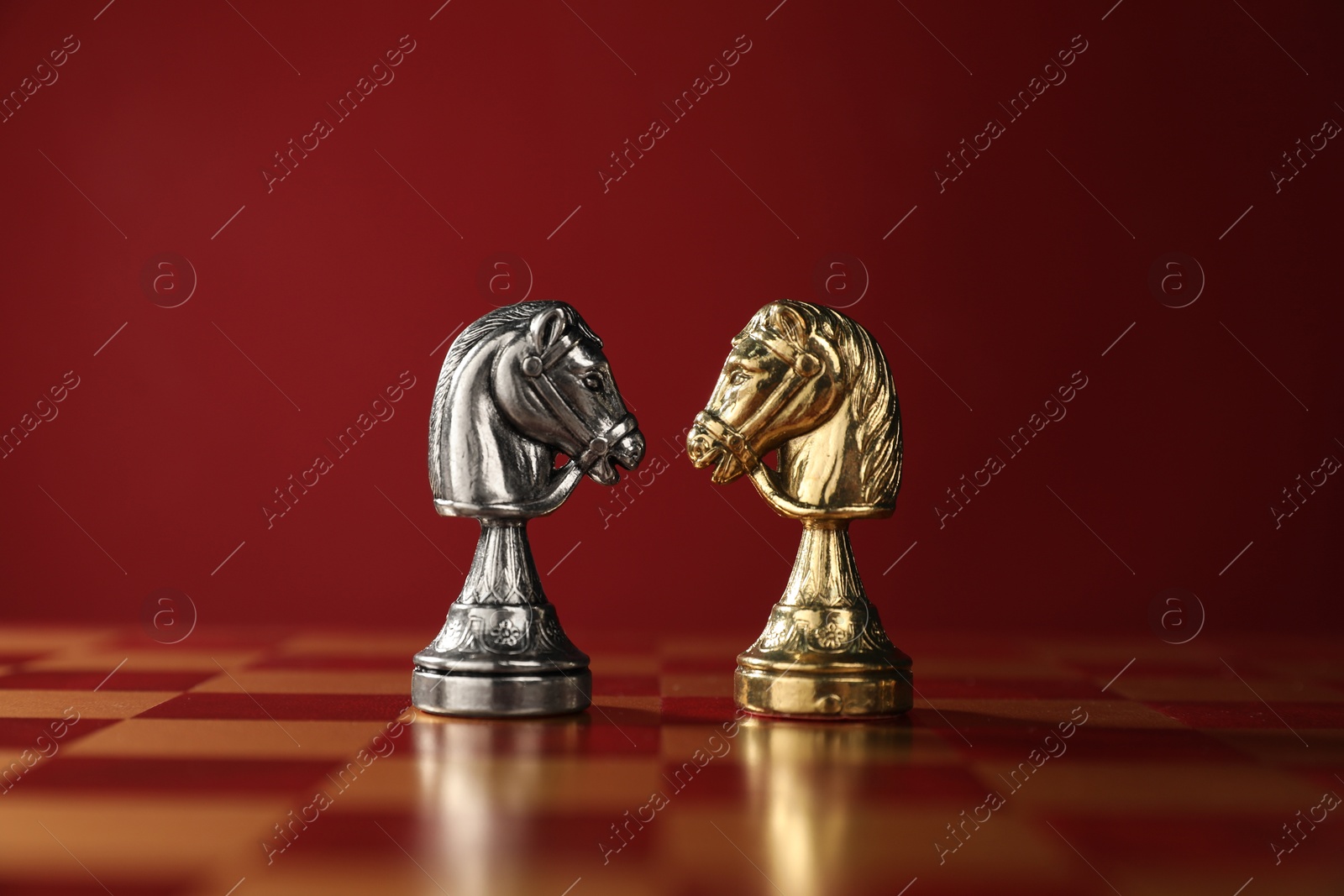 Photo of Golden and silver chess knights in middle of chessboard. Competition concept