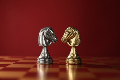 Photo of Golden and silver chess knights in middle of chessboard. Competition concept