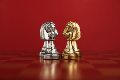 Photo of Golden and silver chess knights in middle of chessboard. Competition concept