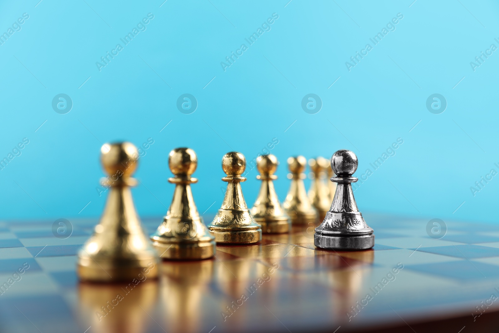 Photo of Silver pawn in front of golden ones on chessboard, closeup. Competition concept