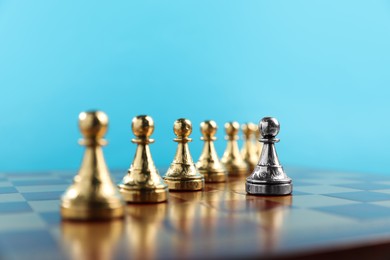 Photo of Silver pawn in front of golden ones on chessboard, closeup. Competition concept