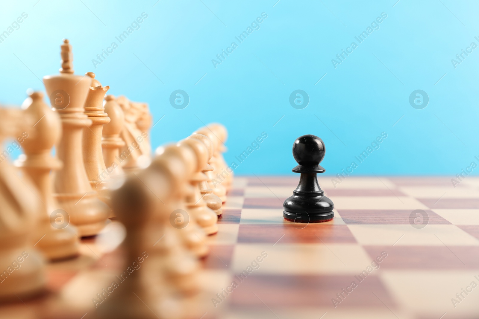 Photo of Black pawn in front of other white chess pieces on chessboard. Competition concept