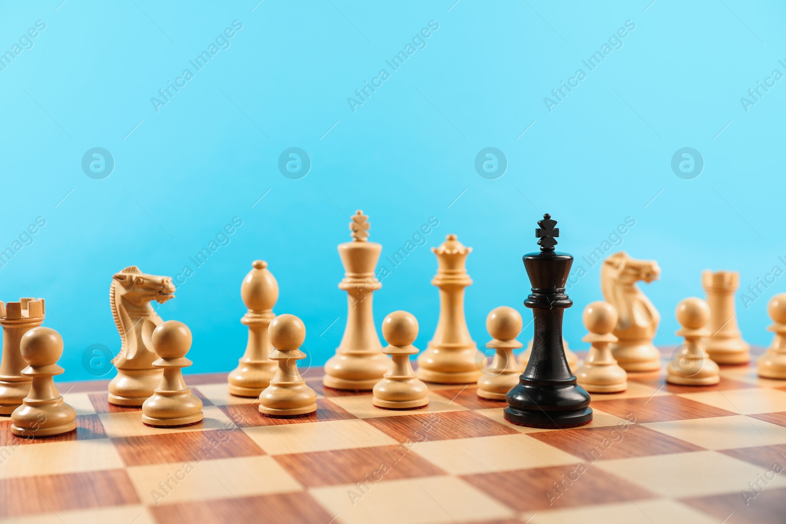 Photo of Black king in front of other white chess pieces on chessboard. Competition concept