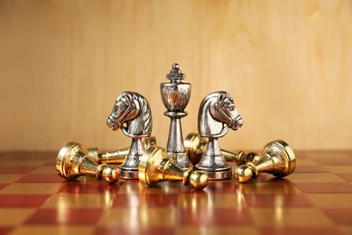 Photo of Silver chess pieces among fallen golden ones on chessboard. Competition concept