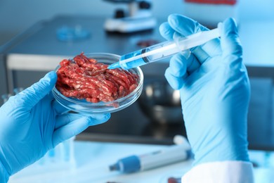 Photo of GMO concept. Scientist injecting something into minced meat in laboratory, closeup