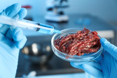 Photo of GMO concept. Scientist injecting something into minced meat in laboratory, closeup