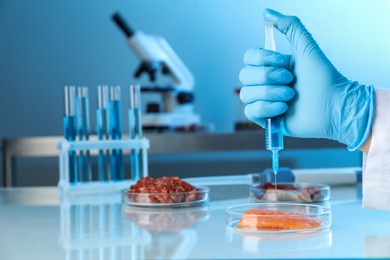 Photo of GMO concept. Scientist injecting something into piece of salmon at table in laboratory, closeup