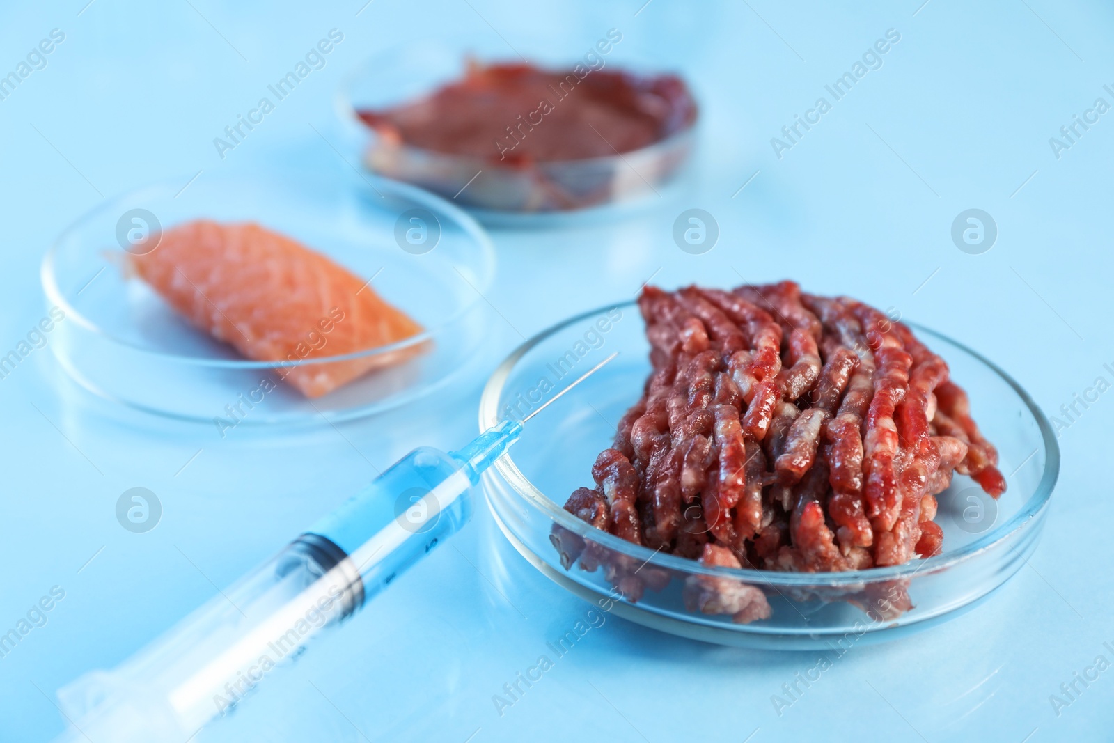 Photo of GMO concept. Minced meat and syringe on table in laboratory, closeup