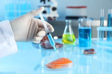 Photo of GMO concept. Scientist injecting something into piece of salmon at table in laboratory, closeup