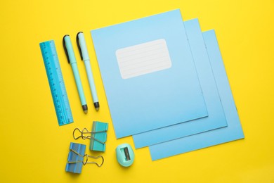 Photo of Flat lay composition with copybooks and other school stationery on yellow background