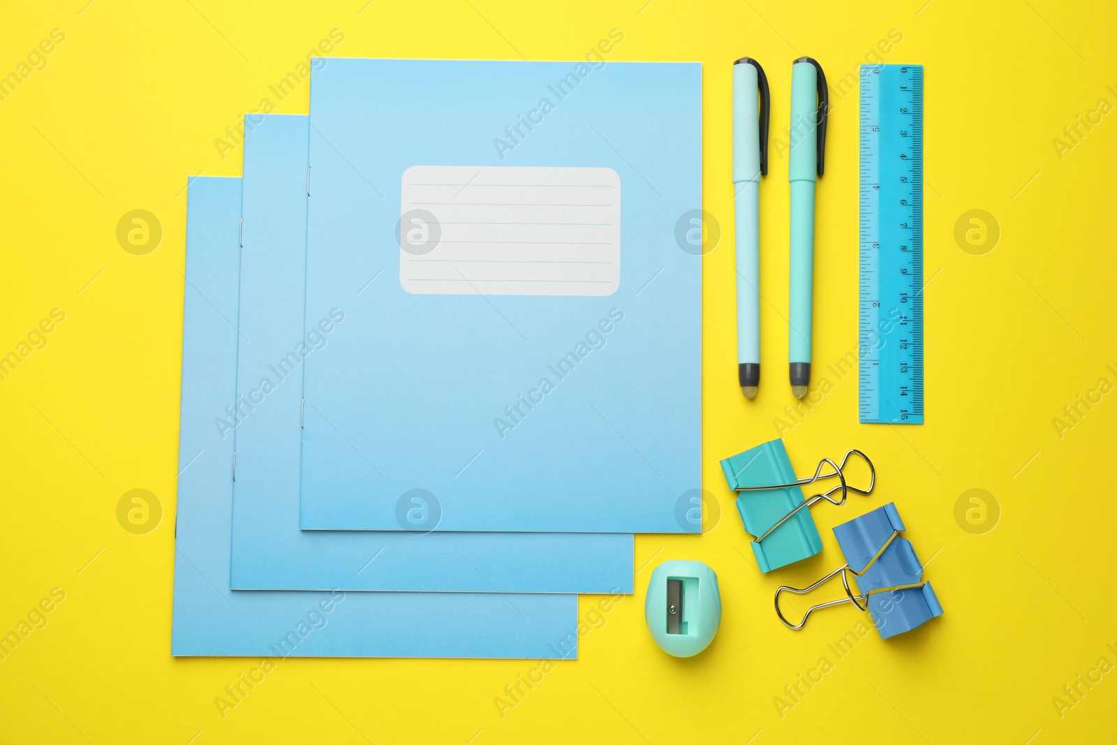 Photo of Flat lay composition with copybooks and other school stationery on yellow background